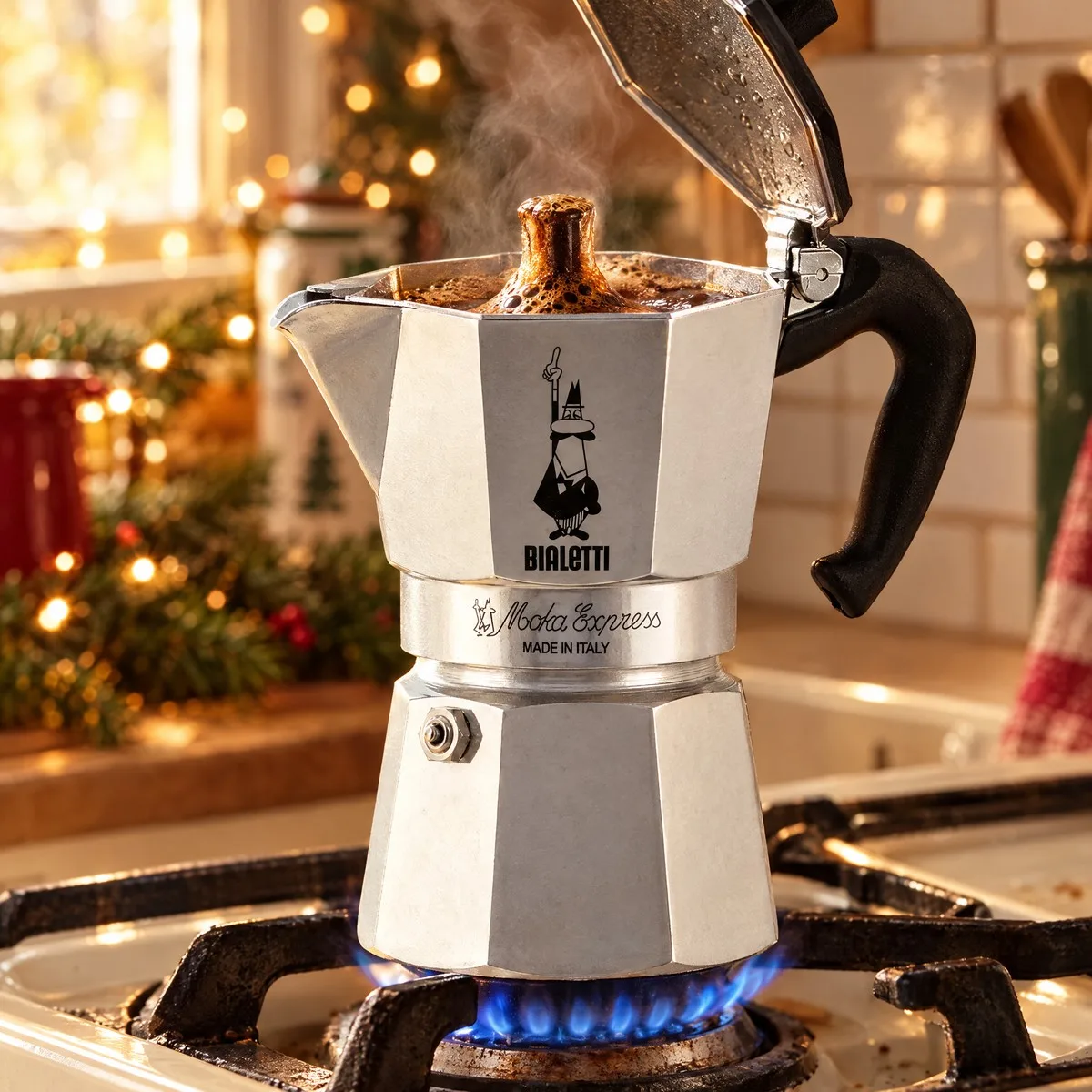 Moka Bialetti na chama do fogão a gás com a tampa aberta e o café escuro subindo e borbulhando