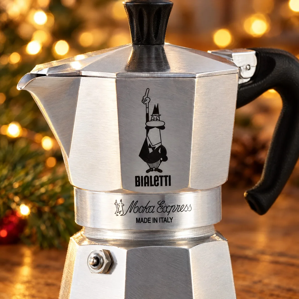 Detalhe da moka Bialetti mostrando as faces octogonais de alumínio, o bonequinho de bigode e a inscrição Moka Express